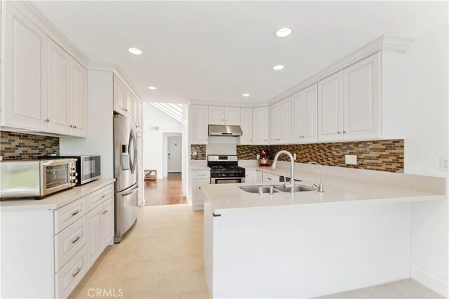 kitchen featuring decorative backsplash, kitchen peninsula, white cabinets, and stainless steel appliances