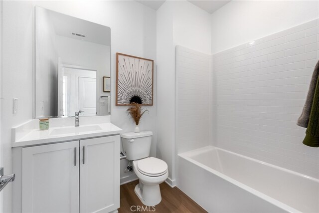 bathroom featuring visible vents, toilet, vanity, shower / tub combination, and wood finished floors