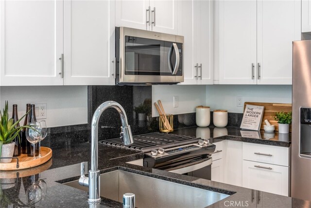 kitchen featuring appliances with stainless steel finishes, white cabinetry, and a sink