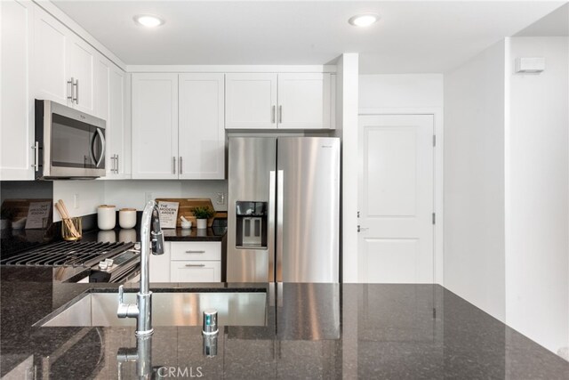 kitchen featuring dark stone counters, stainless steel appliances, recessed lighting, and white cabinets