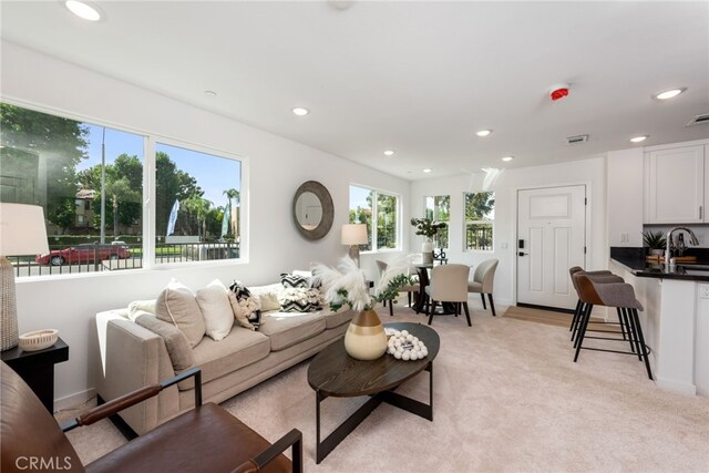 living area featuring light carpet, baseboards, visible vents, and recessed lighting