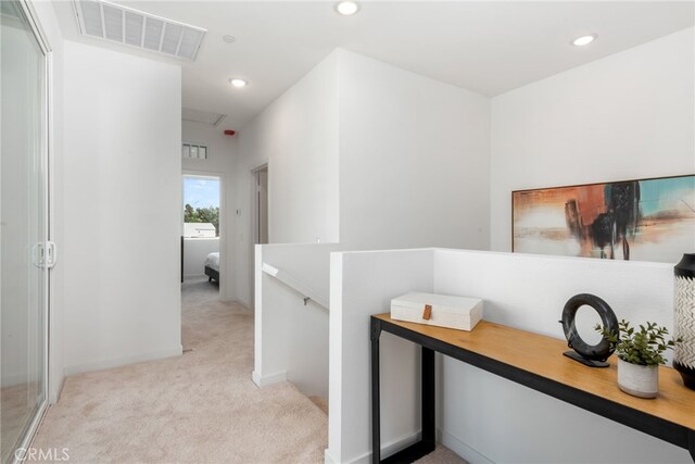 hall with recessed lighting, visible vents, light colored carpet, and an upstairs landing