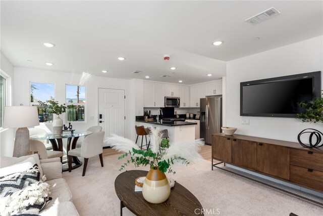 living area with recessed lighting, visible vents, and light carpet