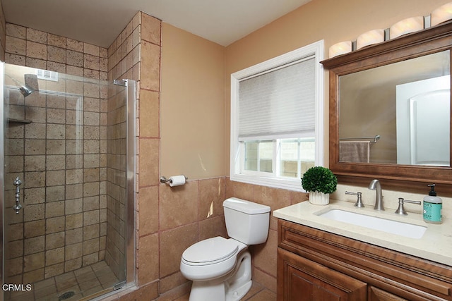 bathroom featuring vanity, tile walls, a shower with door, and toilet