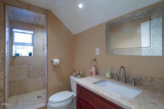 bathroom featuring tiled shower, vanity, vaulted ceiling, and toilet