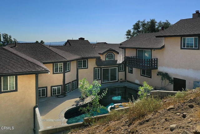 rear view of property featuring a balcony and a patio area