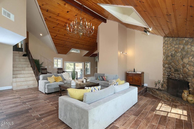 living room with high vaulted ceiling, a stone fireplace, wood ceiling, and an inviting chandelier