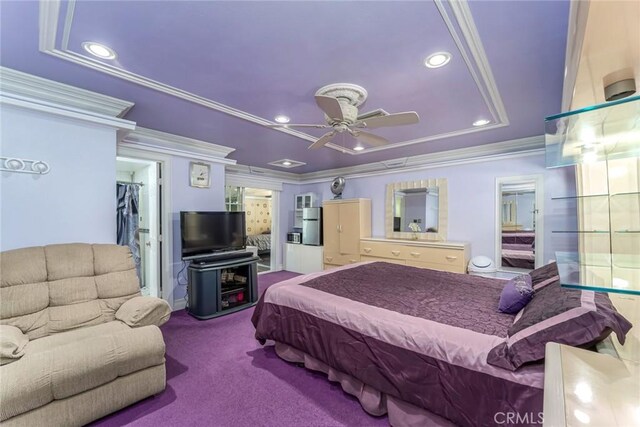 bedroom with ceiling fan, ornamental molding, ensuite bath, carpet, and a tray ceiling