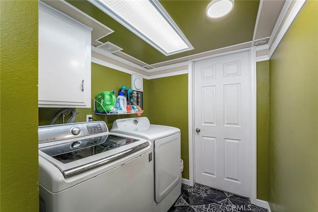 washroom featuring cabinets, ornamental molding, dark tile patterned flooring, and washer and clothes dryer