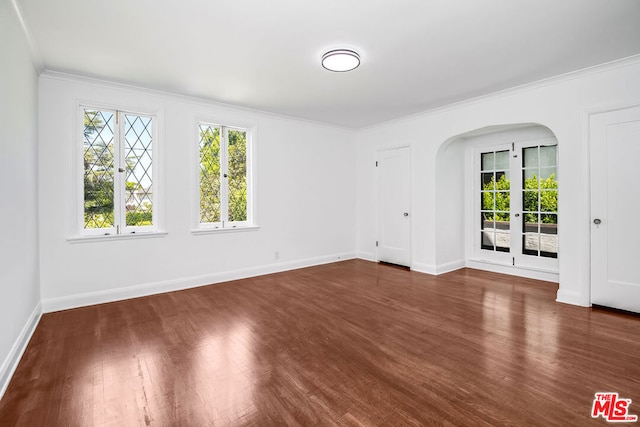 empty room with dark wood-type flooring, ornamental molding, and french doors