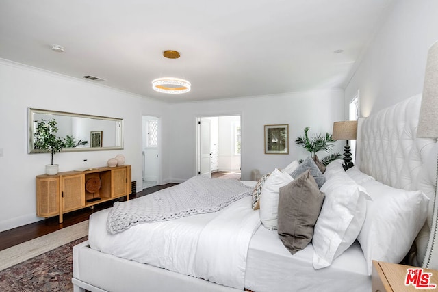 bedroom featuring ensuite bathroom, dark hardwood / wood-style flooring, and crown molding