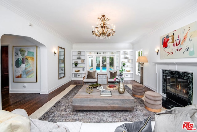 living room with dark wood-type flooring, built in shelves, crown molding, and a fireplace