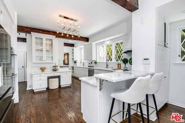 kitchen with kitchen peninsula, dark hardwood / wood-style flooring, light stone countertops, white cabinets, and beamed ceiling