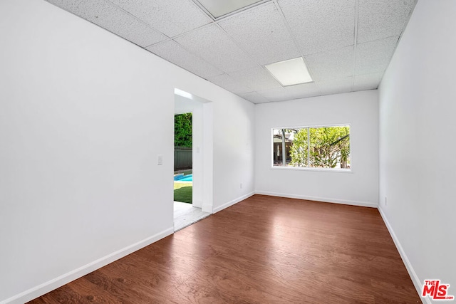 unfurnished room featuring a paneled ceiling and dark hardwood / wood-style flooring