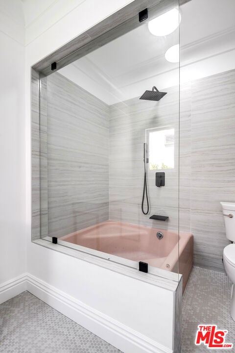 bathroom with tile walls, tiled shower / bath combo, toilet, and tile patterned flooring