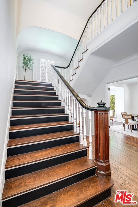 stairs featuring hardwood / wood-style flooring and a towering ceiling