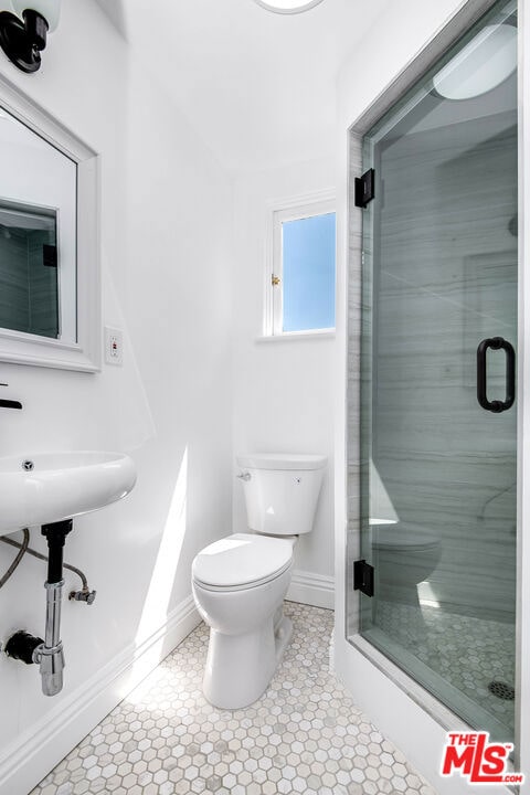 bathroom with toilet, tile patterned floors, and walk in shower