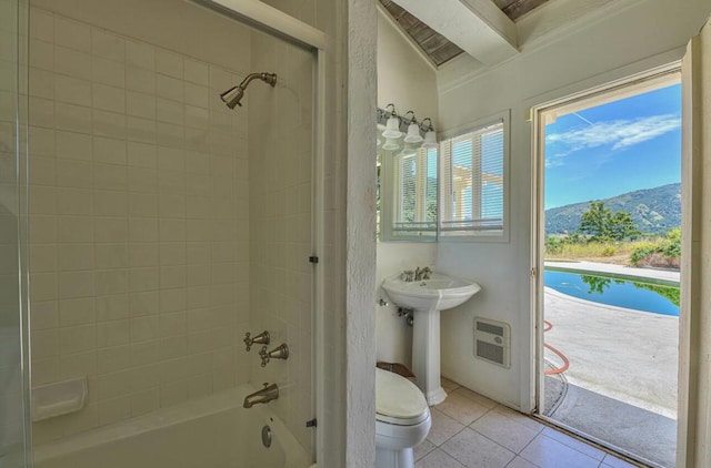 full bathroom with tiled shower / bath, tile patterned flooring, toilet, a mountain view, and heating unit