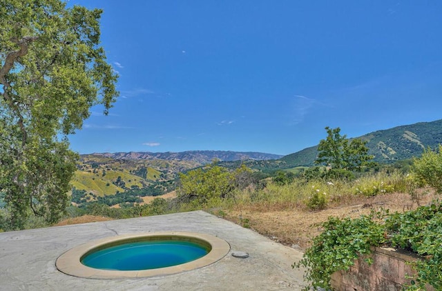 view of swimming pool featuring a mountain view, a patio, and an in ground hot tub