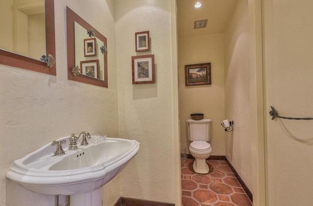 bathroom featuring toilet, tile patterned floors, and sink