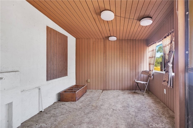 carpeted empty room with wooden walls and wood ceiling