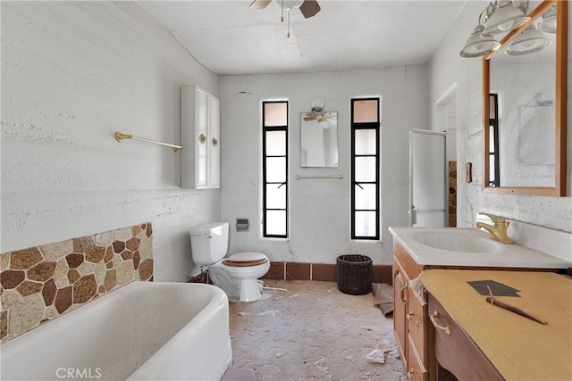 bathroom featuring a tub to relax in, toilet, vanity, and ceiling fan