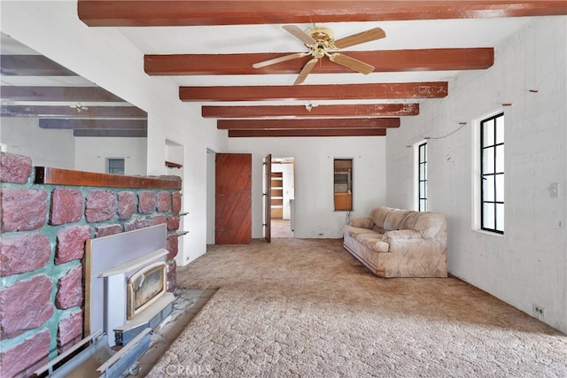 living room featuring a fireplace, carpet floors, beam ceiling, a wood stove, and ceiling fan