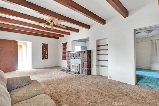 living room with beam ceiling, a wood stove, carpet flooring, and ceiling fan