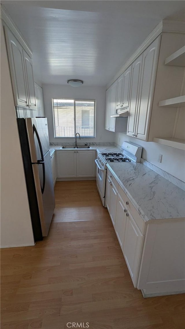 kitchen featuring white cabinets, stainless steel fridge, white gas range, and sink