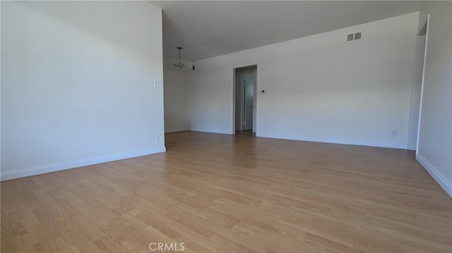 unfurnished room with an inviting chandelier and light wood-type flooring