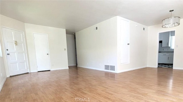 spare room featuring light wood-type flooring and an inviting chandelier