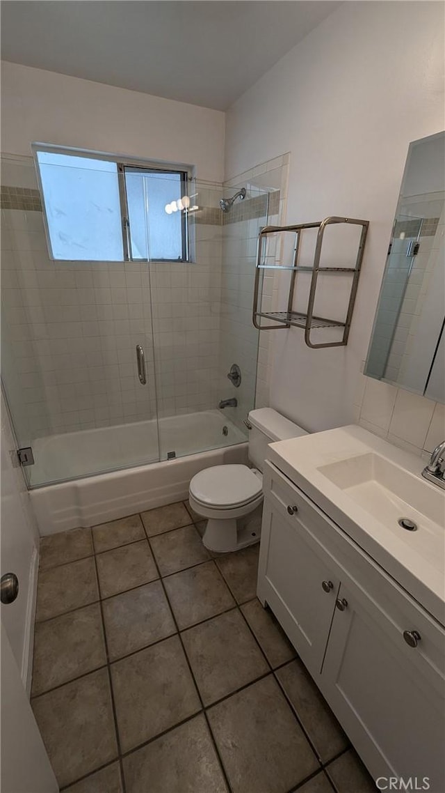 full bathroom with tile patterned flooring, vanity, toilet, and bath / shower combo with glass door