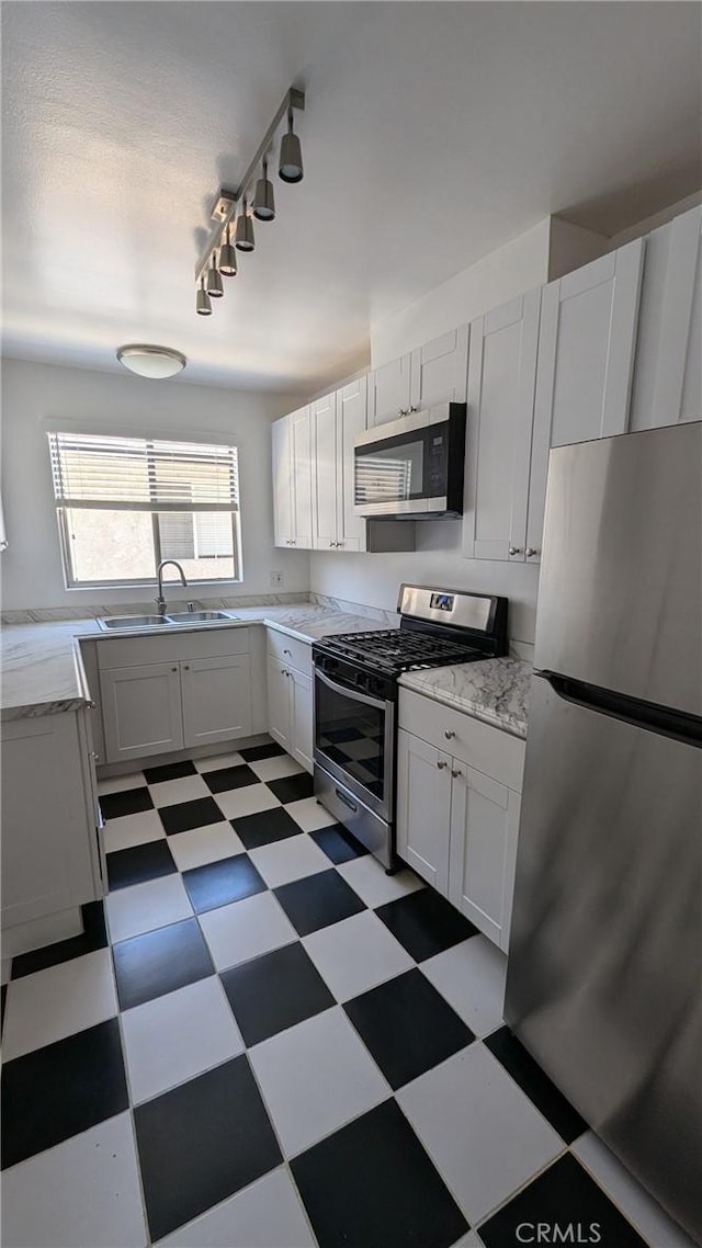 kitchen featuring sink, white cabinets, stainless steel appliances, and rail lighting