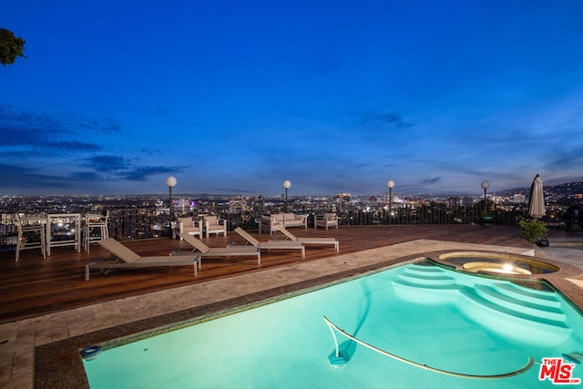 pool at dusk featuring an in ground hot tub and a wooden deck