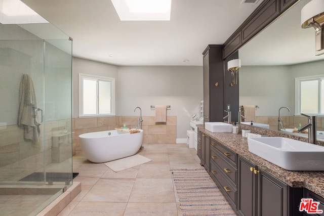 bathroom featuring a wealth of natural light, plus walk in shower, double vanity, and tile patterned flooring