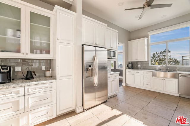 kitchen with decorative backsplash, ceiling fan, white cabinetry, appliances with stainless steel finishes, and sink