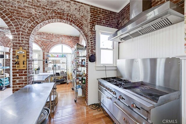455 W 20th St, Merced, CA 95340 - kitchen with brick wall, light hardwood / wood-style flooring, and wall chimney exhaust hood