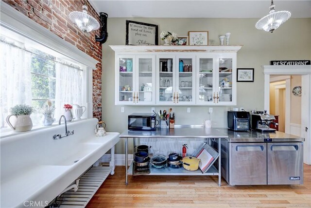 455 W 20th St, Merced, CA 95340 - bar with hanging light fixtures, white cabinetry, brick wall, and light hardwood / wood-style floors