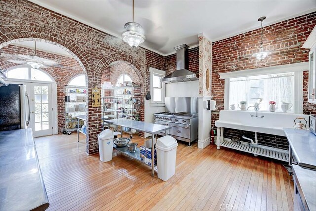 455 W 20th St, Merced, CA 95340 - kitchen featuring an inviting chandelier, light wood-type flooring, stainless steel fridge, brick wall, and wall chimney range hood