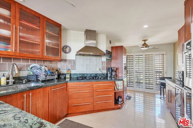 kitchen with decorative backsplash, sink, dark stone countertops, and wall chimney range hood