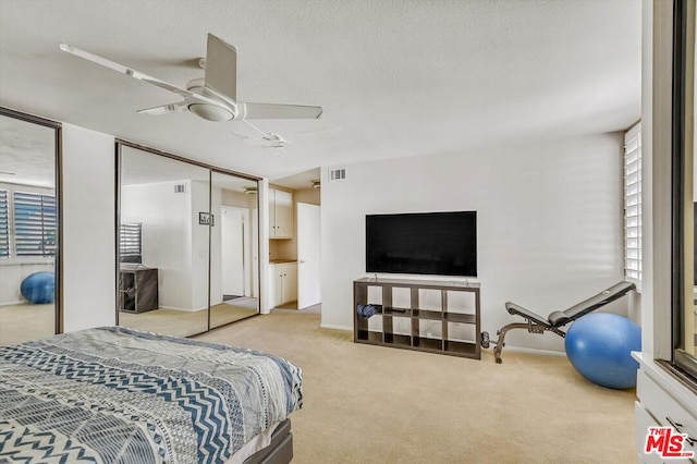 bedroom featuring a textured ceiling, light colored carpet, and ceiling fan