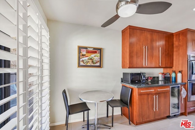 kitchen with ceiling fan, stainless steel double oven, light tile patterned floors, and beverage cooler