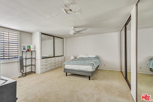 bedroom featuring light carpet, a textured ceiling, and ceiling fan