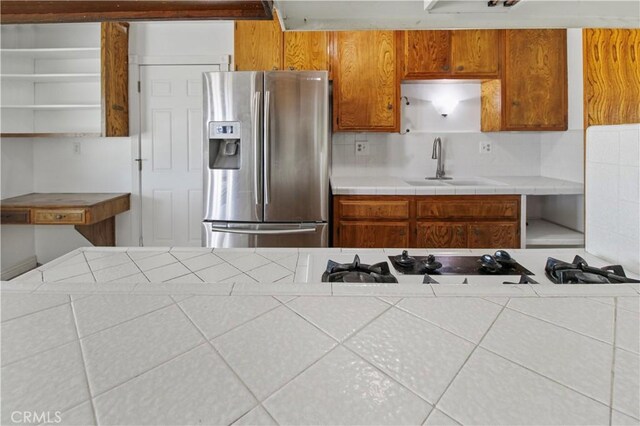 kitchen featuring stainless steel fridge with ice dispenser, tasteful backsplash, and sink