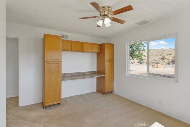 unfurnished bedroom featuring ceiling fan, a textured ceiling, and light colored carpet