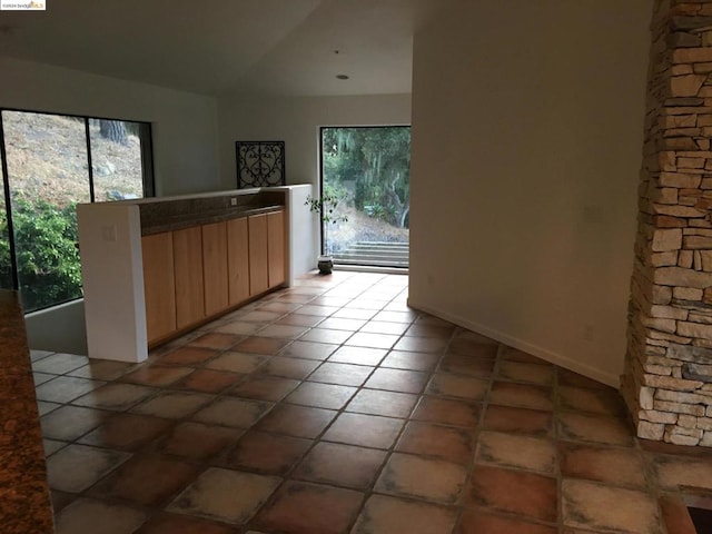 interior space featuring lofted ceiling, light brown cabinetry, and tile patterned flooring