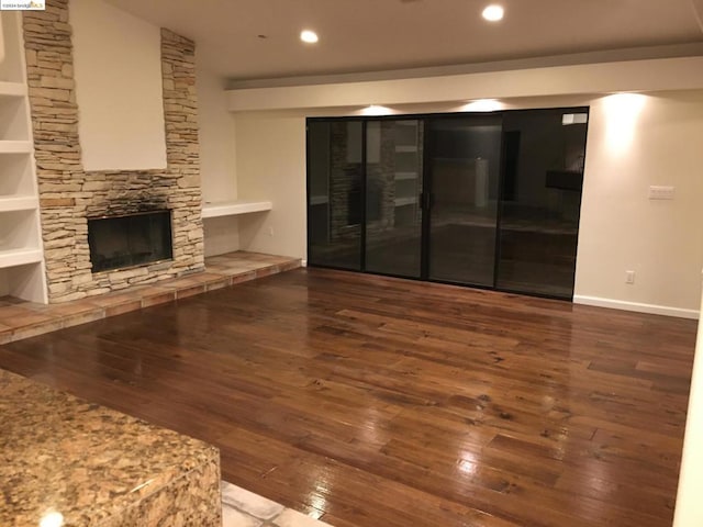 unfurnished living room with a fireplace, built in features, and hardwood / wood-style floors