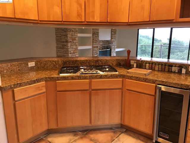 kitchen featuring stainless steel gas stovetop, beverage cooler, decorative columns, and light tile patterned flooring