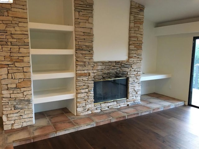 unfurnished living room featuring wood-type flooring and a stone fireplace