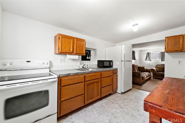 kitchen featuring tile counters, sink, white appliances, and light tile patterned floors